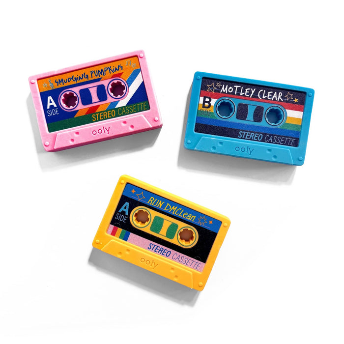 Three retro cassette tape-shaped erasers on a white background: a pink one labeled 'SMUDGING PUMPKINS', a blue one labeled 'MOTLEY CLEAR', and a yellow one labeled 'RUN DMCLEAN'. Each has 'ooly' printed near the bottom.