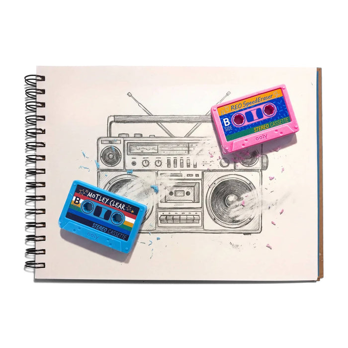 A spiral-bound sketchbook page featuring a hand-drawn sketch of a boombox, with two retro cassette tape erasers placed on top: one blue labeled 'MOTLEY CLEAR' and one pink labeled 'REO SpeedEraser'.