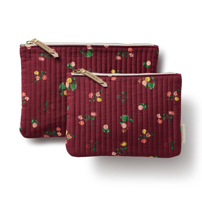 Two quilted fabric pouches in a deep burgundy color with a small multicolor floral print, shown on a clean white background. One pouch is nested inside the other, both featuring gold-toned metal zippers with light leather pull tabs.