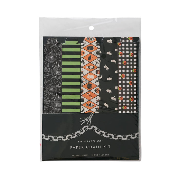 Rifle Paper Co. Paper Chain Kit in a clear plastic hanging bag, featuring five Halloween-themed patterned paper strips: spiderwebs, green and black stripes, orange diamonds with halloween motifs, white ghosts on black, and black and white gingham with pumpkins.