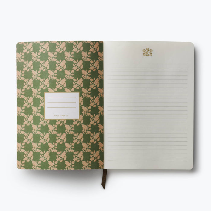 An open notebook with a green and beige floral patterned cover on the left and lined blank pages on the right, photographed on a clean white background.