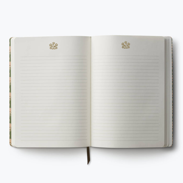 An open lined notebook with cream pages, featuring a small gold floral emblem printed near the top of each page. The notebook is photographed flat against a clean white background.