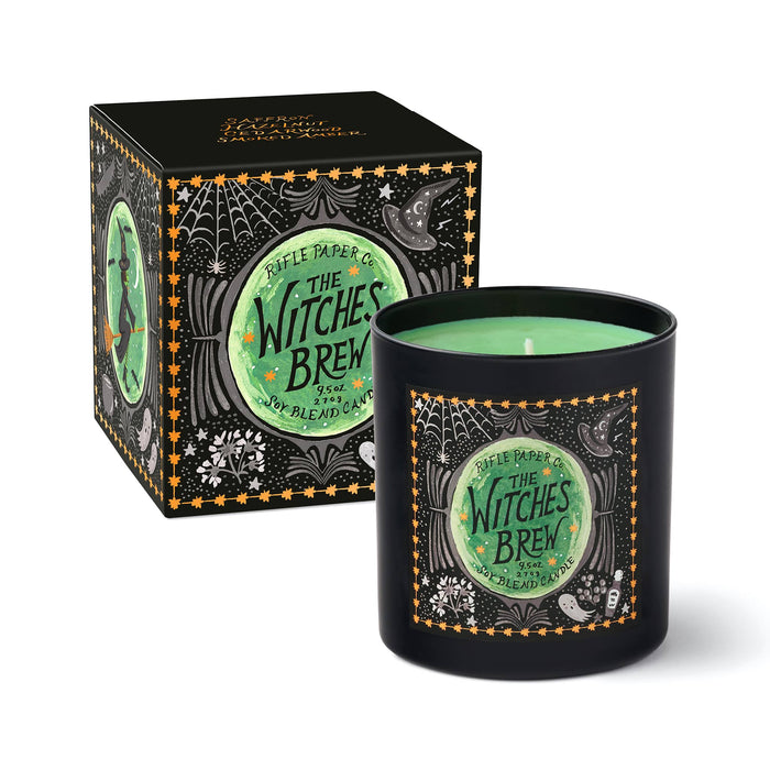 A black candle jar with a green wax fill and a decorative front label reading 'Rifle Paper Co. The Witches Brew,' shown beside its matching black box on a white background.