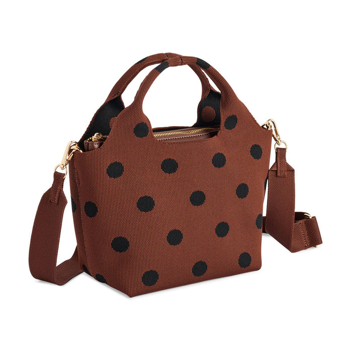 A brown handbag with black polka dots, featuring dual top handles, a top zipper, and an adjustable crossbody strap with gold-tone hardware, front angle view, shown on a plain white background.
