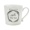 White mug with 'spill the tea' text and decorative wreath on a white background.
