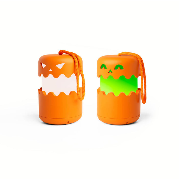 Two orange jack-o'-lantern-shaped portable light with hanging cords, shown side by side on a white background. The left speaker has a white glowing face, and the right speaker has a green glowing face.