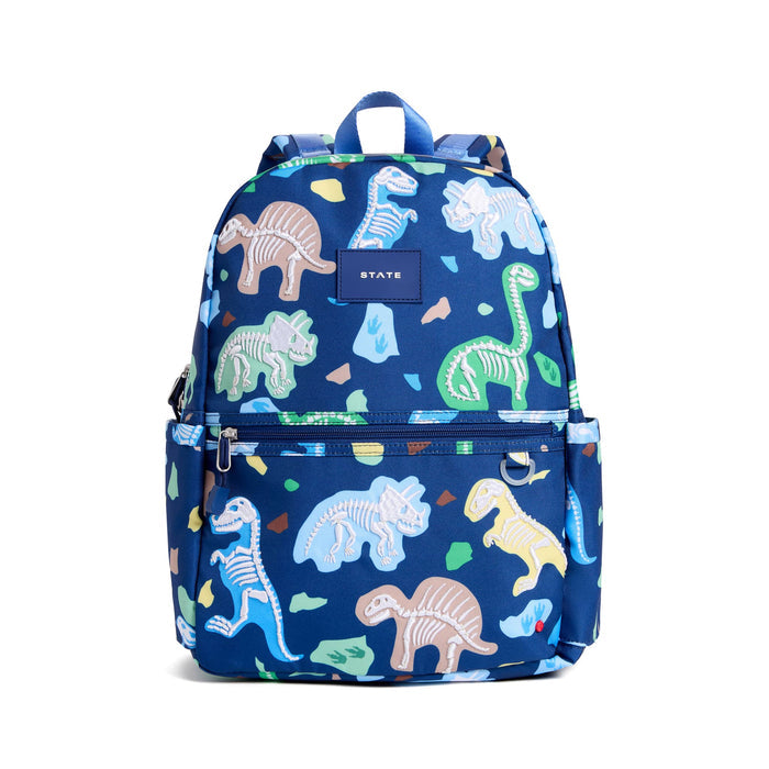 A blue backpack with an all-over dinosaur skeleton print, featuring a front zippered pocket and a central brand patch that reads STATE. Front view on a plain white background.