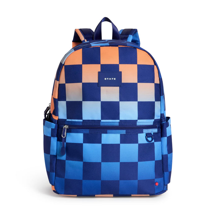A backpack with a navy blue checkerboard pattern on a blue and orange gradient backdrop, featuring a front zippered pocket and a small 'STATE' label, front view on a plain white background.