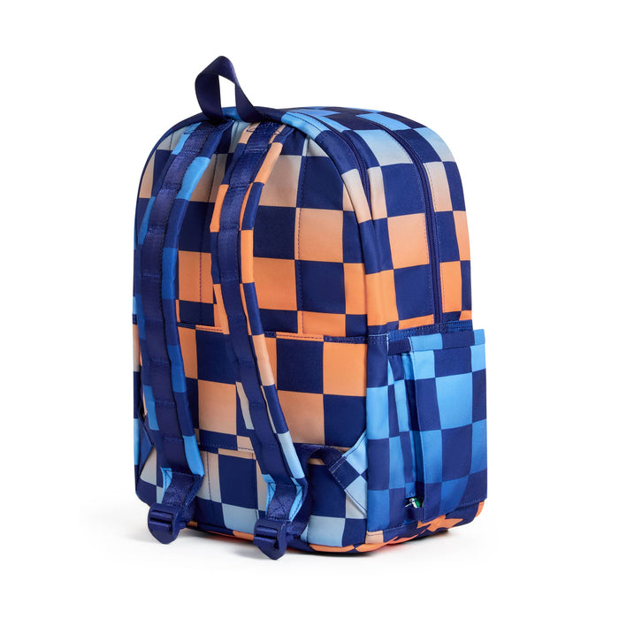 A backpack with a navy blue checkerboard pattern on a blue and orange gradient backdrop, shown from the back on a plain white background.