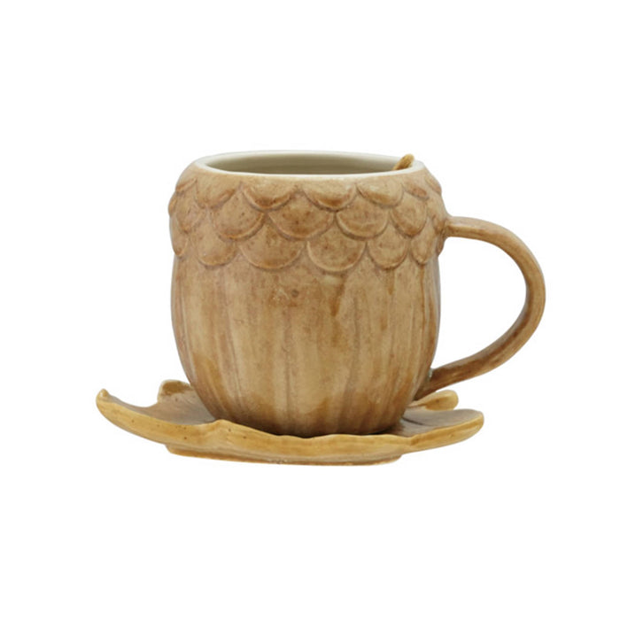 A light brown ceramic mug shaped like an acorn with a leaf-shaped saucer, shown on a plain white background.