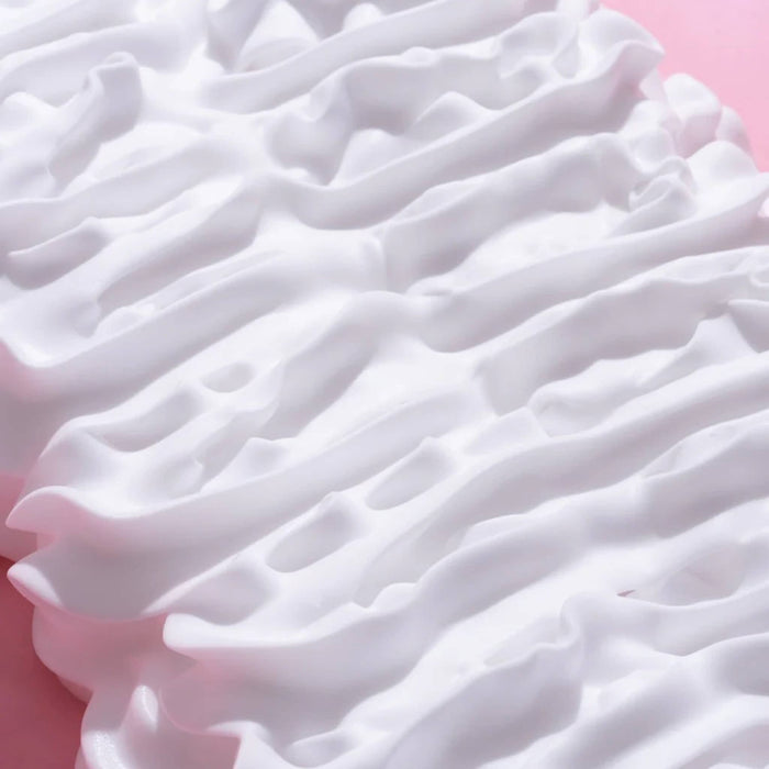 Close-up of white whipped body wash, on a pink background.