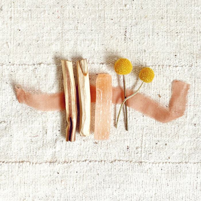 Sunny Side palo santo bundle with pink selenite and dried yellow craspedia flowers unrolled with vintage peach colored ribbon.