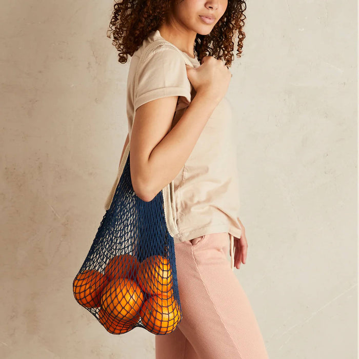 Pillowpia The French Market Bag in Navy, with oranges, on model's shoulder.