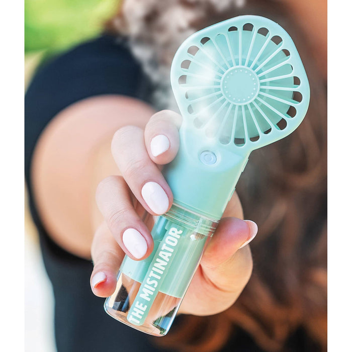 Mini rechargeable fan with misting function in mint green,being held by a person outside.