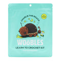 Front of teal pouch packaging for The Woobles Charlie the Roach beginner crochet kit, on a white background.