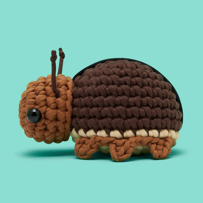 Crocheted roach toy, side view, on a teal background.