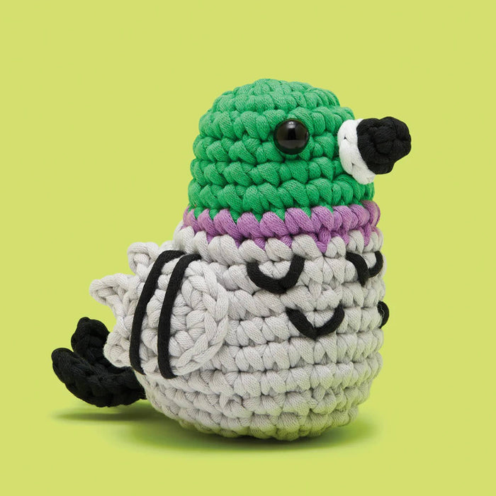 Crocheted pigeon with green head, purple chest, and gray body on a lime green background.