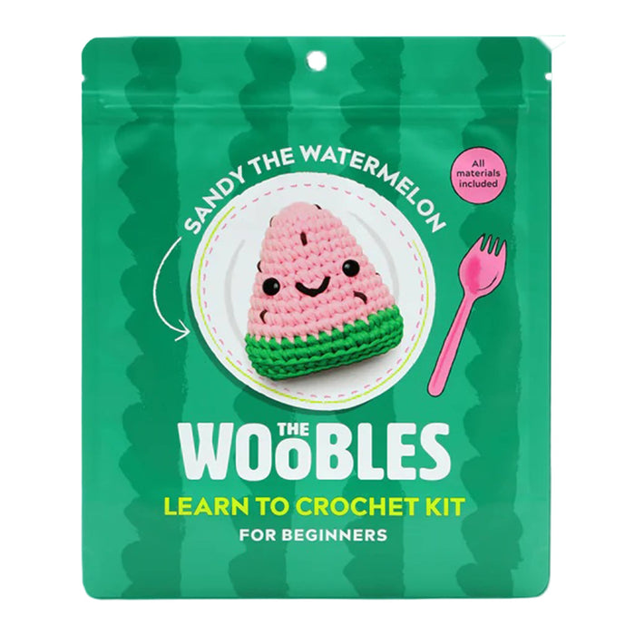 Front of green pouch packaging for The Woobles Sandy the Watermelon beginner crochet kit, on a white background.