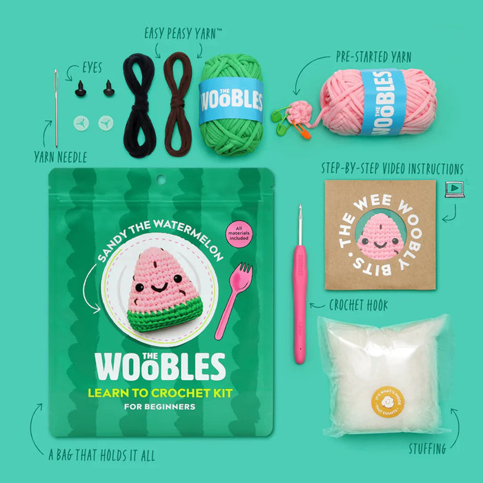 Green pouch packaging for The Woobles Sandy the Watermelon beginner crochet kit, with contents, on a green background.