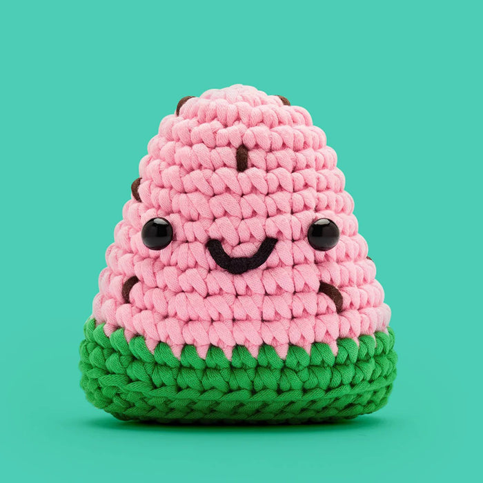 Crocheted pink and green watermelon slice on a green background.