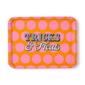 A rectangular tray with rounded corners, featuring a bright orange background with large pink polka dots and the words 'Tricks & Treats' in stylized lettering across the center, shown on a plain white background.