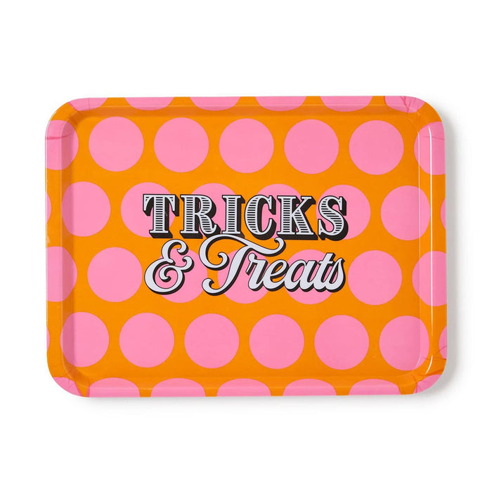 A rectangular tray with rounded corners, featuring a bright orange background with large pink polka dots and the words 'Tricks & Treats' in stylized lettering across the center, shown on a plain white background.