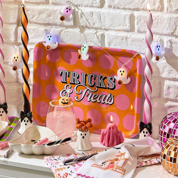 Halloween-themed tray with 'Tricks & Treats' text, surrounded by decorative items on a white brick wall background.