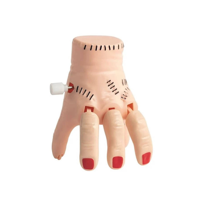 A plastic wind-up toy hand with stitched details, red fingernails, and a white winding knob on a plain white background.