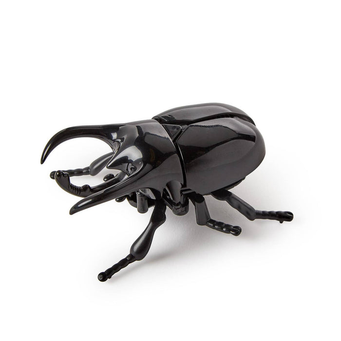 A glossy black wind up toy beetle with long curved pincers and detailed legs, photographed on a clean white background.