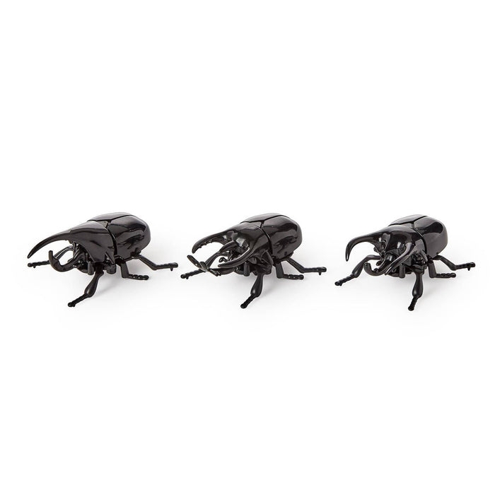 Three glossy black wind up toy beetles with pincers and detailed legs, photographed on a clean white background.