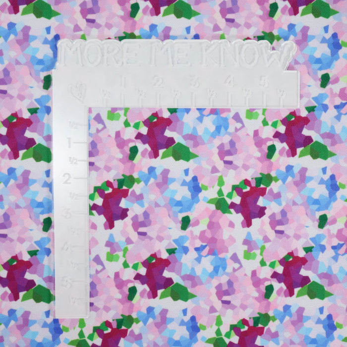 This printed WPC shows geometric shapes to resemble bunches of flowers. The colors are in an array of pinks, blues, and greens on a white background. This photo shows a white L shaped ruler for scale.