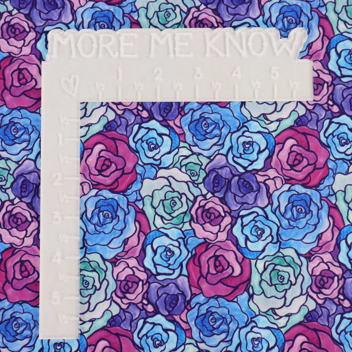This printed WPCotton has a rose design varying in shades of blue, green, purple, and pink. This photo shows a white L shaped ruler for scale.