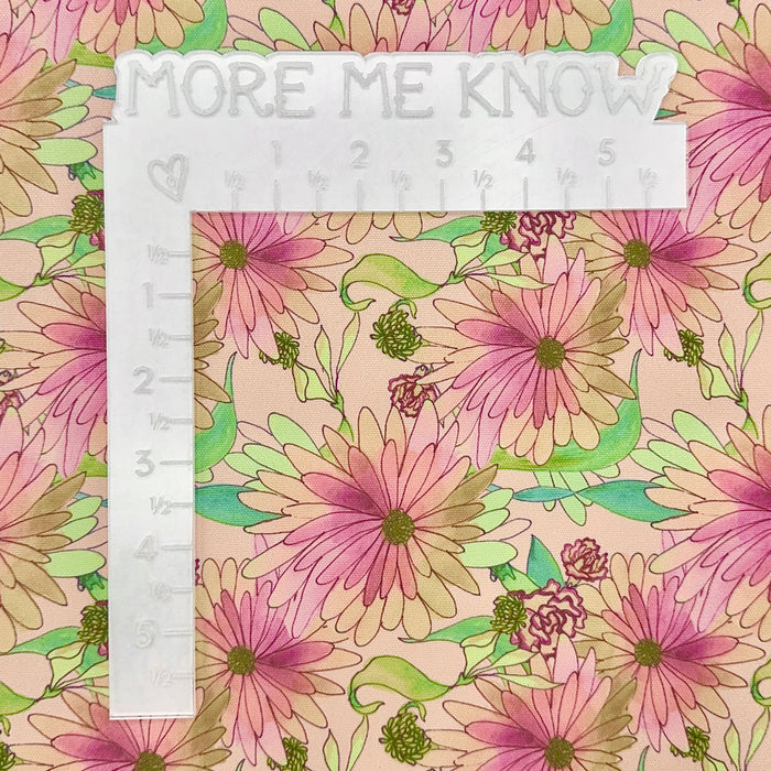 This printed WPCotton features daisy flowers in shades of pink, orange, and green. This photo shows a white L shaped ruler for scale.