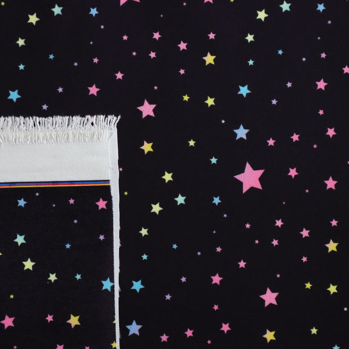 This WPCotton has pastel rainbow stars in a variety of sizes on a black background.