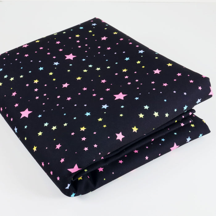 This WPCotton has pastel rainbow stars in a variety of sizes on a black background. This photo is of the fabric folded.