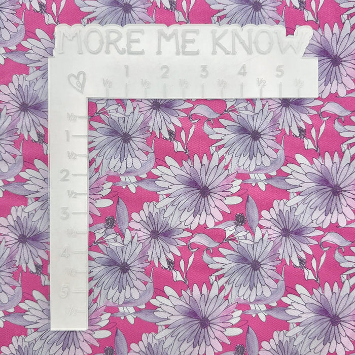 This printed WPCotton features daisy flowers in hues of pink and purple on a saturated pink background. This photo has a white L shaped ruler for scale.