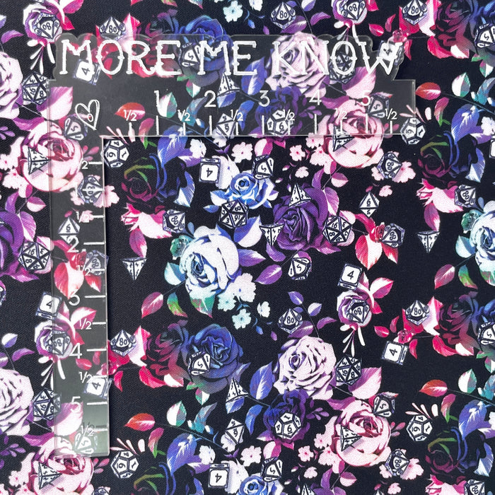 This printed WPCotton features a design with roses in a blue to pink to green ombre and different types of dice on top. This photo shows an L shaped ruler for scale.