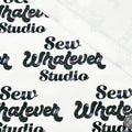 This printed WPCotton features the "Sew Whatever Studio" logo in black with multicolored spools of thread in the wording on a white background.