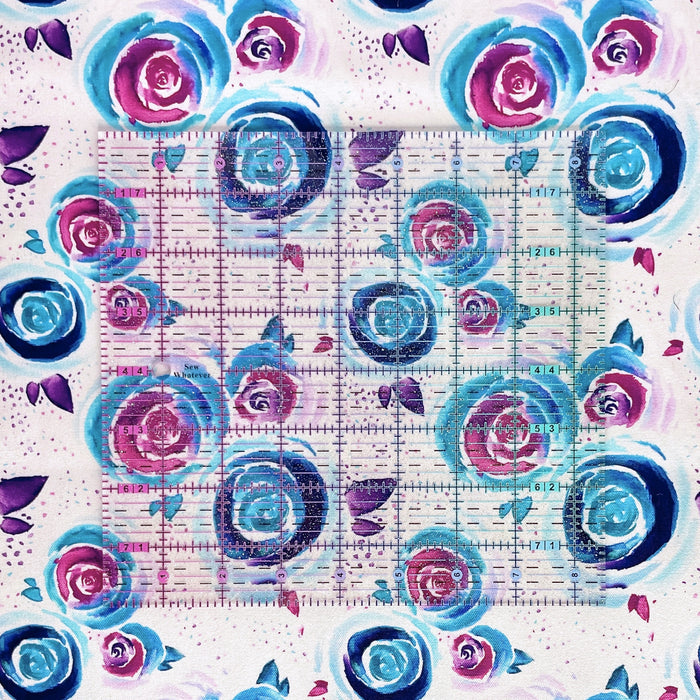 This printed WPCotton features watercolor roses in shades of blue and pink on a pale background. This photo shows a ruler on top of the fabric for scale.