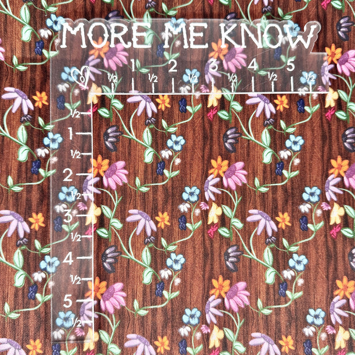This printed WPCotton consists of different colorful flowers on a wood-esque background. This photo has an L shaped ruler for scale.