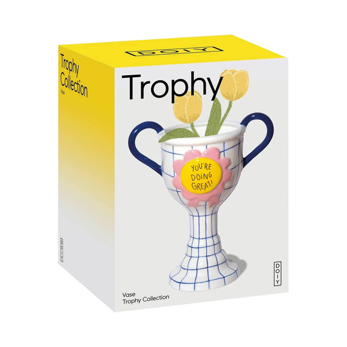 The product packaging box for the DOIY Trophy Collection vase, featuring a white and yellow box with an illustration of a blue-and-white trophy vase holding yellow tulips with a pink rosette, with a yellow center reading 'YOU'RE DOING GREAT!'.
